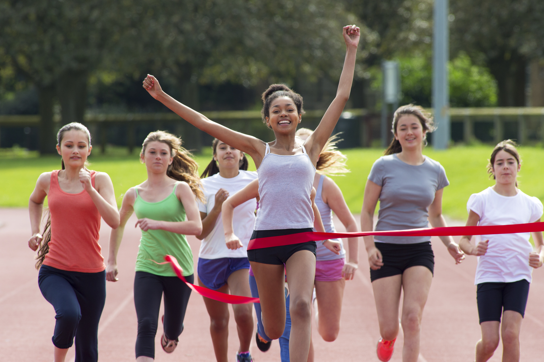 Girls crossing a finish line on a running track.