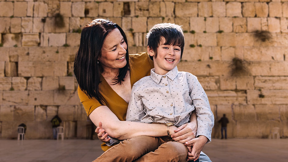 A mother holds her smiling son in front of the Western Wall in Jerusalem